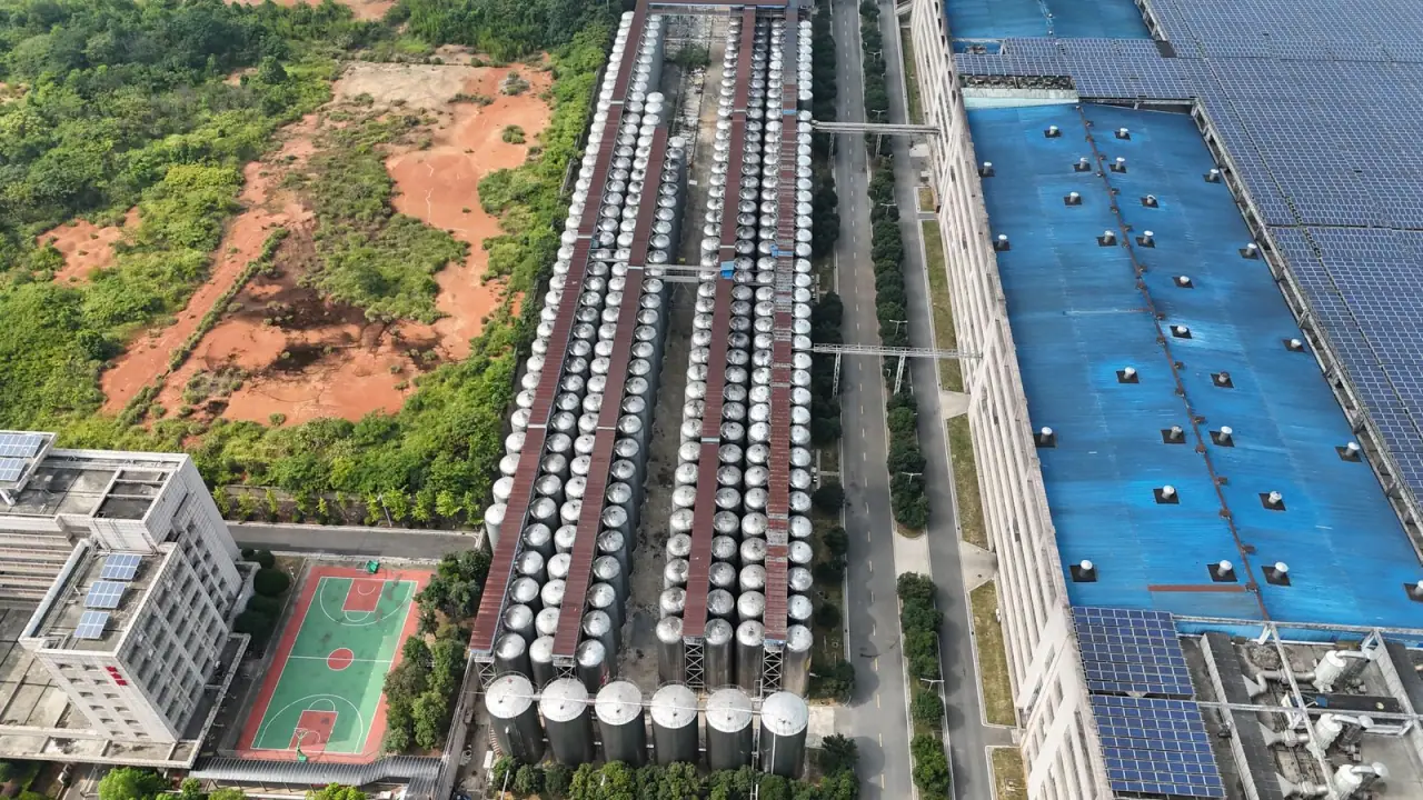 A factory with a fully covered solar roof and storage silos, seen from the air