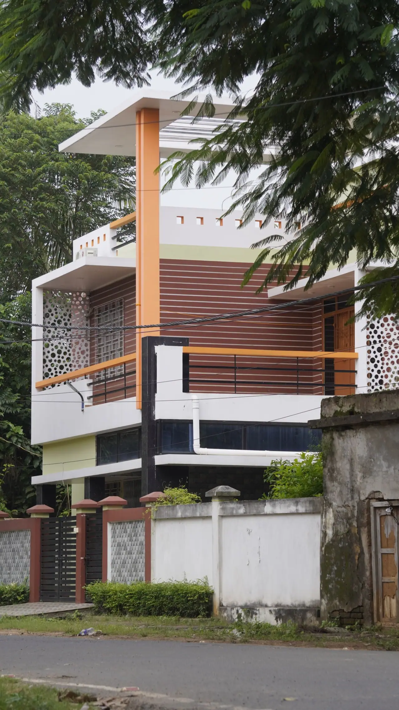 A contemporary Indian house with a projecting concrete canopy and timber screen