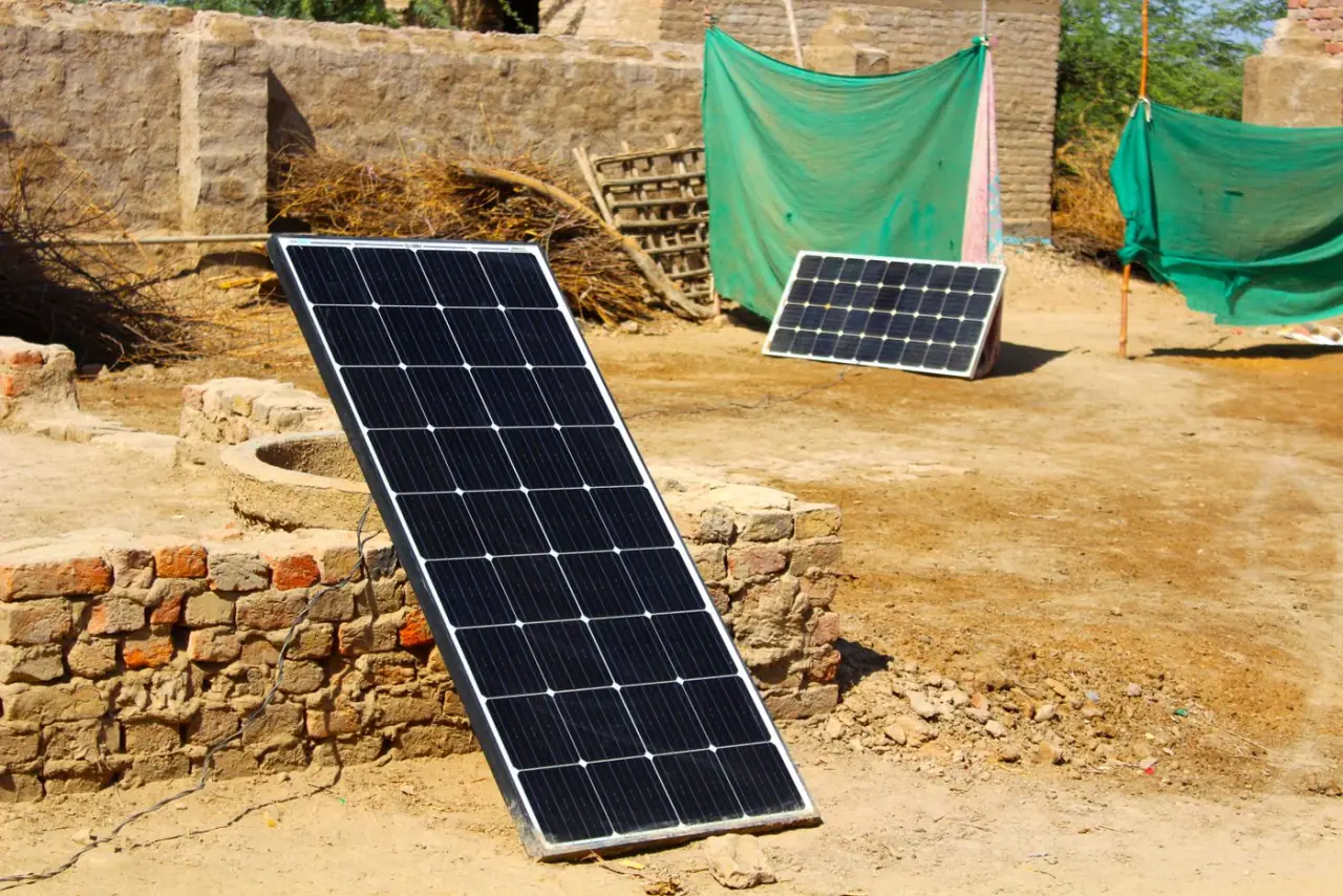 Two solar modules on a simple ground frame beside a rural boundary wall